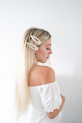 Naklejka premium Blonde hair girl with white pearl hair clips in hair, white background