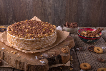 Delicious honey cake with sweet sour cream, chocolate and nuts on a rustic background. View from above. Free space for text.