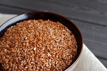 flax seeds in bowl with linen fabric on wooden background