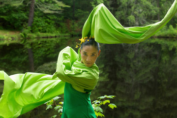 Dancer in green dress with very long sleeves in Connecticut woods.