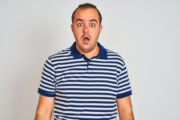 Obraz premium Young man wearing casual striped polo standing over isolated white background In shock face, looking skeptical and sarcastic, surprised with open mouth