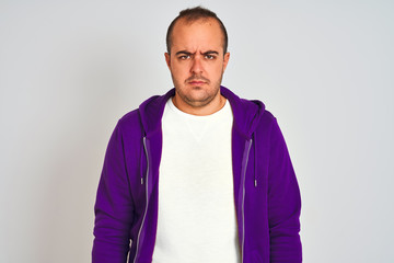 Young man wearing purple sweatshirt standing over isolated white background skeptic and nervous,...