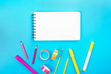 School items as a frame on blue background. Trendy colors, flat lay style. Back to school concept.
