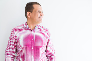 Middle age man wearing business shirt over white wall looking to side, relax profile pose with natural face with confident smile.