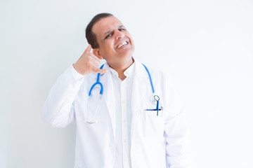 Middle age doctor man wearing stethoscope and medical coat over white background smiling doing phone gesture with hand and fingers like talking on the telephone. Communicating concepts.