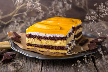 Sliced banana cake from chocolate biscuit with jelly cream. A piece of dessert on wooden boards.