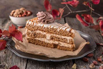 Sliced honey cake with caramel and meringue. A piece of dessert on wooden boards.