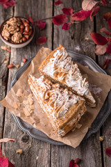 Sliced honey cake with nuts and meringue. A piece of dessert on wooden boards.