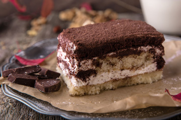 Sliced Tiramisu cake made of chocolate and white sponge. A piece of dessert on wooden boards.