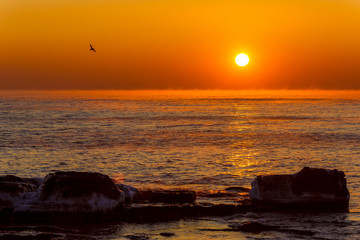 Beautiful seascape. The orange sun rises over the horizon in a blazing sea.