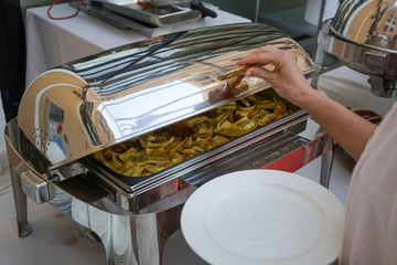 Woman taking food from a buffet line