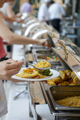 Woman taking food from a buffet line