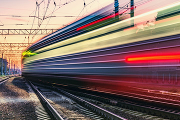 Passenger train moves fast at sunset time.