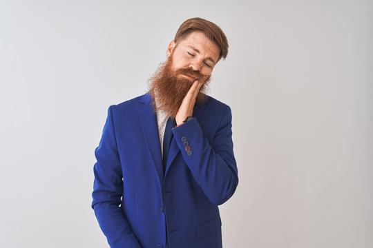 Young redhead irish businessman wearing suit standing over isolated white background thinking looking tired and bored with depression problems with crossed arms.