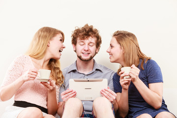 Friends relaxing browsing internet on tablet.