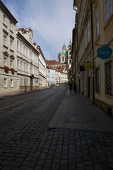 Fototapeta na wymiar Couple waling down an empty street in Prague early in the morning
