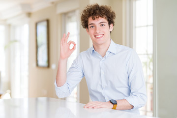 Fototapeta na wymiar Young business man with curly read head smiling positive doing ok sign with hand and fingers. Successful expression.
