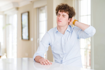 Young business man with curly read head Suffering of neck ache injury, touching neck with hand, muscular pain