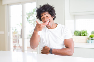 Fototapeta na wymiar Young african american man wearing casual white t-shirt sitting at home laughing at you, pointing finger to the camera with hand over body, shame expression