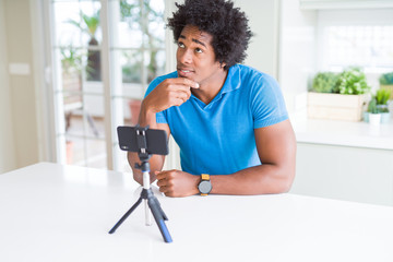 African American man doing online call with webcam using smartphone serious face thinking about question, very confused idea