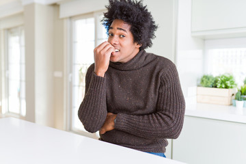 Fototapeta na wymiar African American man wearing winter sweater looking stressed and nervous with hands on mouth biting nails. Anxiety problem.