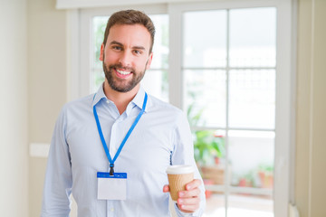 Handsome business man wearing id bagde with a big smile on face while drinking take away coffee in...