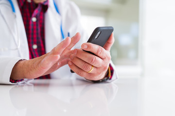 Close up of doctor man hands using smartphone and wearing stethoscope