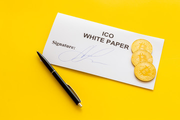 White paper ICO, coins, pen on yellow background