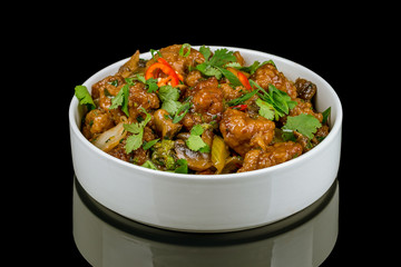 Chinese chicken in sweet and sour sauce on black glass with reflection
