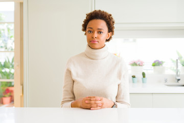 Young beautiful african american woman at home with serious expression on face. Simple and natural looking at the camera.