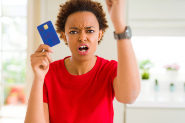 Young african american woman holding credit card annoyed and frustrated shouting with anger, crazy and yelling with raised hand, anger concept