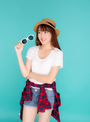 Beautiful portrait young asian woman wear hat and holding sunglasses smiling confident enjoy journey summer trip in vacation isolated on blue background, tourist asia girl cheerful with travel.