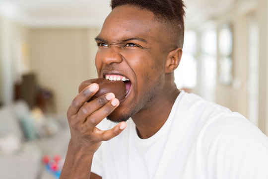 African american man eating  and enjoying a sweet chocolate donut