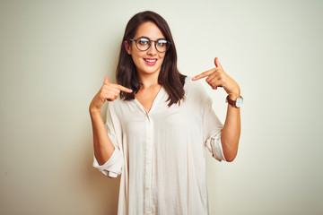 Young beautiful woman wearing shirt and glasses standing over white isolated background with serious expression on face. Simple and natural looking at the camera.