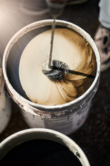 Bucket with mixing paint for wall, diy concept.