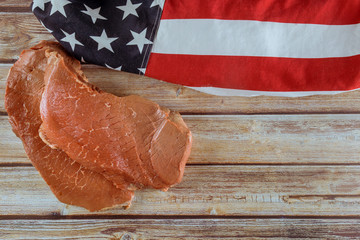 Raw beef strip loin steak on a wood background and flag of USA