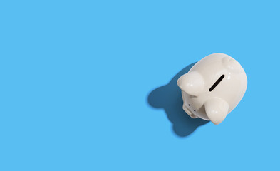 A white piggy bank overhead view flat lay