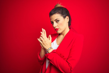 Young beautiful business woman standing over red isolated background Holding symbolic gun with hand gesture, playing killing shooting weapons, angry face