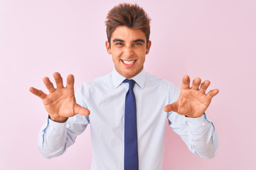 Young handsome businessman wearing shirt and tie standing over isolated pink background smiling funny doing claw gesture as cat, aggressive and sexy expression
