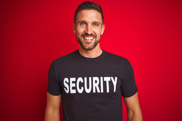 Young safeguard man wearing security uniform over red isolated background with a happy and cool...