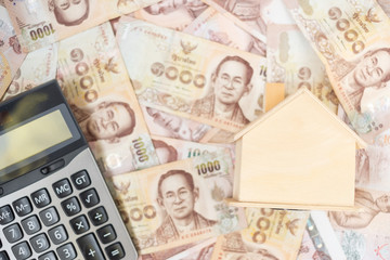 Wood house model, calculator and money , Thai baht banknote. real estate, Property investment, home mortgage financial and savings concepts