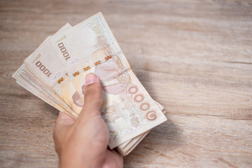Businessman hand holding Thai Baht banknote stack. business, money, planning, finance and Saving for the future concepts