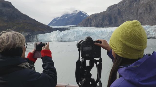 Alaska Glacier Bay Tourists looking at landscape using binoculars and taking pictures on cruise ship. People on vacation travel looking at Margerie Glacier and wildlife cruising famous destination.