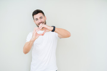 Young handsome man wearing casual white t-shirt over isolated background smiling in love showing heart symbol and shape with hands. Romantic concept.