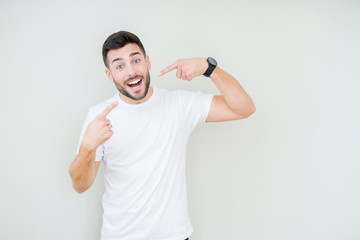 Young handsome man wearing casual white t-shirt over isolated background smiling confident showing and pointing with fingers teeth and mouth. Health concept.