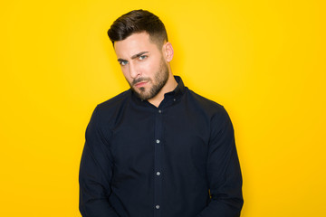 Young handsome man possing and modeling over yellow isolated background