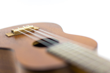 Fototapeta premium Close-up head of dark wooden ukulele music instrument Hawaiian guitar body with selected focus and copy space isolated over white background.