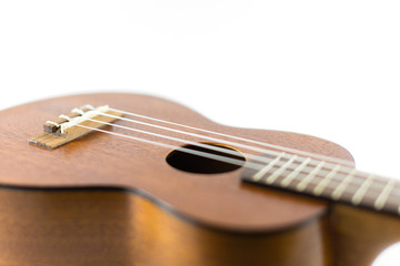 Obraz premium Close-up head of dark wooden ukulele music instrument Hawaiian guitar body with selected focus and copy space isolated over white background.