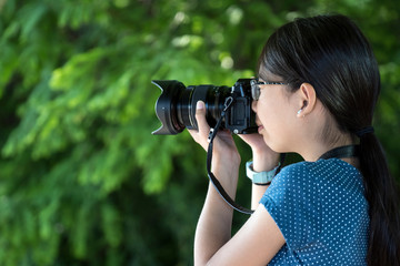 Young little girl photographer with a digital camera taking photo outdoors