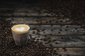 glass of coffee latte with beans on brown wooden background 